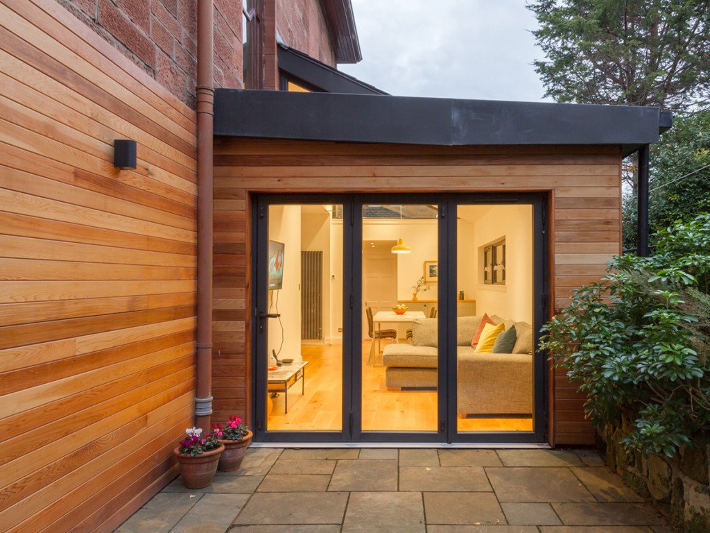 Extension d'une maison en bois. Baie vitrée 3 pans.